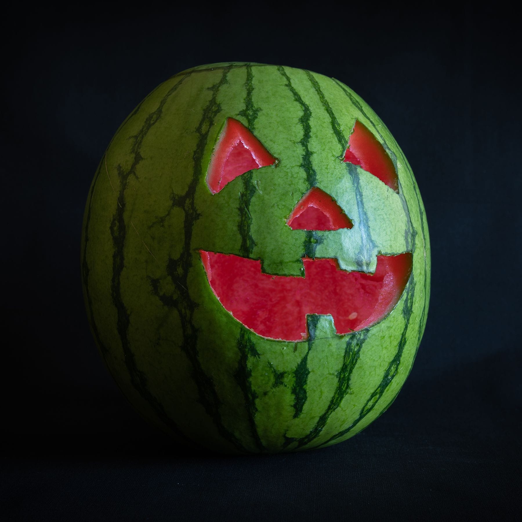 Small watermelon with red interior 7 or 8 inches in diameter. Straight photograph with a second exposure to add the interior lighting. 20 July 2020
